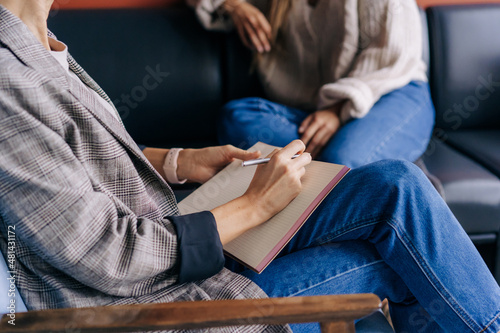 Close-up of a psychologist's hands writing down notes about a patient in a notebook. The psychologist makes a social survey of the reference group. A professional is talking to a client.