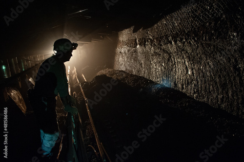 Underground coal mine shaft tunnel drift with miner and light.