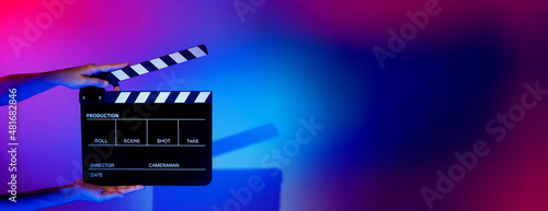 Blurry images of movie slate or clapper board. Hand holds empty film making clapperboard on color background in studio for film movie shooting or recording. Film slate for Youtuber video production.