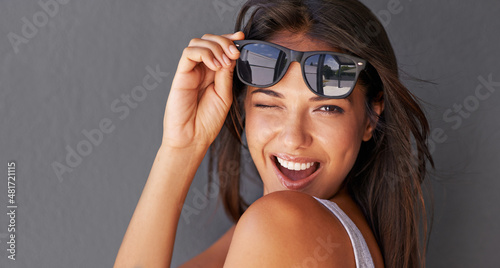 Hey you.... Shot of an attractive young woman winking at the camera while holding up her sunglasses.