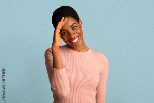 Portrait Of Shy African American Woman Smiling And Touching Head In Embarrassing