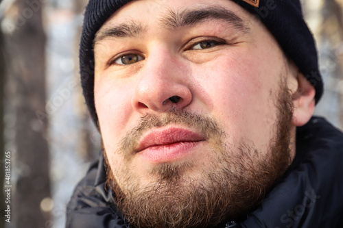 Face of a young man with messy and untrimmed beard and moustache close-up. Selective focus. Outdoors