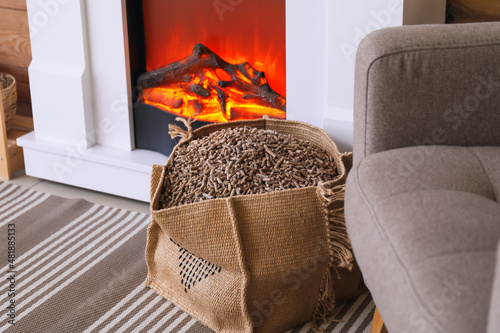 Bag with wood pellets near fireplace in living room
