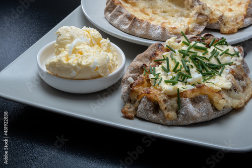 Traditional Finnish foods - Fresh Karelian pies with rice pudding filling and egg butter and chives topping against black background.