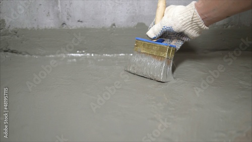 The process of applying mortar - waterproofing to a concrete floor. The concept of waterproofing the floor with a brush.