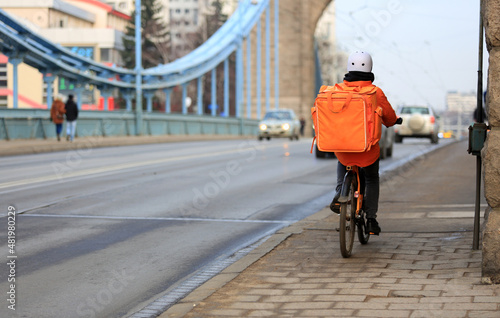 Kurier na rowerze jedzie mostem Grunwaldzkim we Wrocławiu, dostarcza jedzenie. 