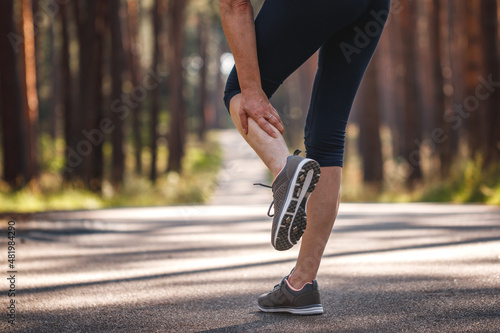 Woman feeling pain of her leg during jogging. Calf muscle cramp. Underestimating the warm-up exercise before running