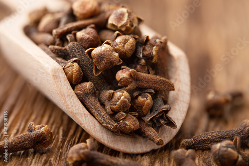 Whole cloves in a wooden scoop close up