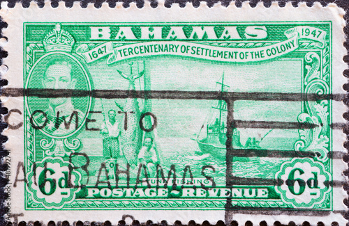 Bahamas - circa 1948: a postage stamp from Bahamas, showing scenes of tuna fishing with a ship at sea and a portrait of King George V