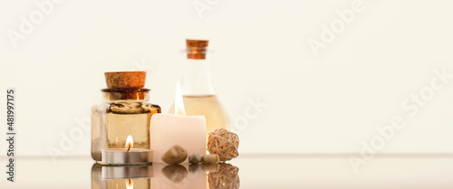 Concise spa composition with oil flasks and candles on beige background.