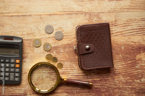 monety, kalkulator ,lupa i brązowy portfel na drewnianym stole ,polski złoty 
