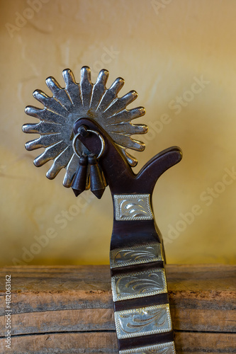 close up on the detail of a beautiful authentic western wear cowboy spur on a wooden shelf