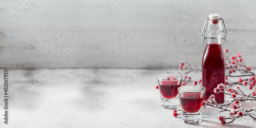 Two glasses of red cocktail, vodka or liqueur on light background. Alcohol shot drink concept