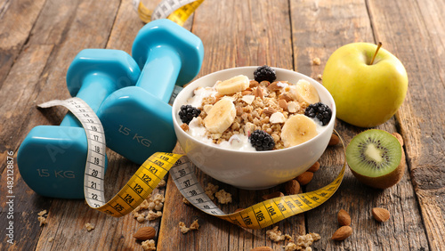 health food concept- muesli, fruits and dumbbell
