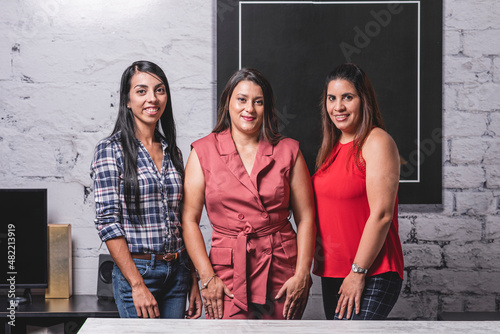 Retrato horizontal tres mujeres latinas profesionales viendo a cámara 