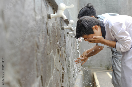 Close up A boarding school student is doing ablution washing his face