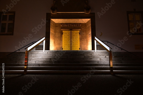 Beleuchtete Tür mit beleuchtetem Geländer einer Treppe in Schweinfurt, Kunsthalle Eingang