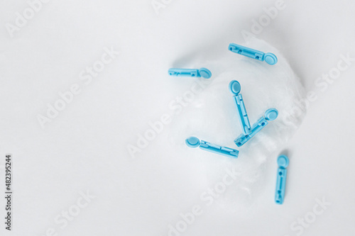 Cotton wool on a white background with blue lancets on it