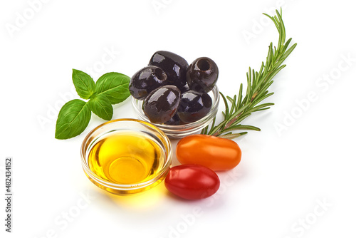 Olive oil in a bowl with tomatoes and olives, isolated on white background.