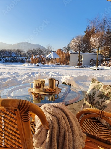 Piknik zimowy pod ciepłym kocem z kubkiem gorącej kawy w pięknym zimowym ogrodzie