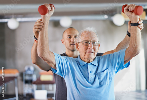You can do it. Shot of a physiotherapist helping a senior man with weights.
