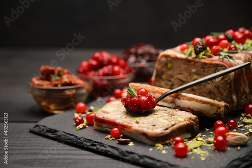 Traditional French terrine covered with bacon on dark wooden background with Christmas decorations
