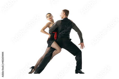 Flexible young couple dancing Argentine tango isolated on white studio background. Artists in black stage costumes
