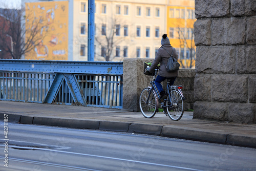 Kobieta jedzie na rowerze z plecakiem ścieżką rowerową po mostem Grunwaldzkim we Wrocławiu. 