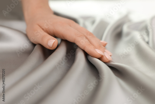 Woman touching smooth silky fabric, closeup view