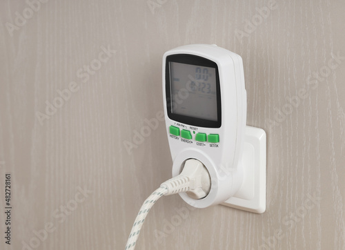 Wattmeter for measuring electricity costs with plug connected to the outlet, saving, expense analysis, in socket on wall