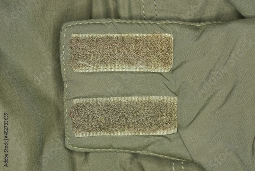 two plastic velcro fasteners on the green fabric of the collar on the jacket