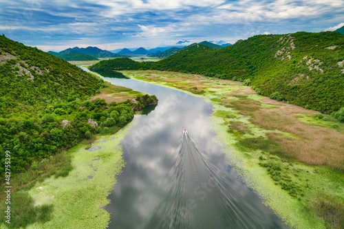 Boat in Skadar Lake with amazing clouds reflections in National Park in Montenegro, aerial view