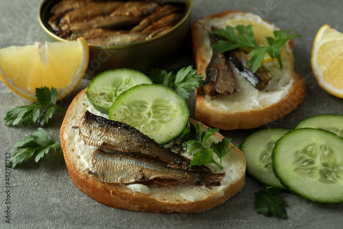 Concept of tasty snack with sandwiches with sprats on gray textured background