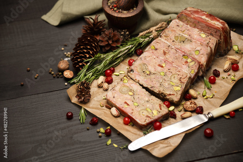 Sliced Traditional French terrine covered with bacon on dark wooden background