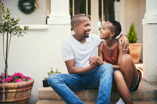 Home is wherever you are, babe. Shot of an affectionate couple sitting on their front door steps.