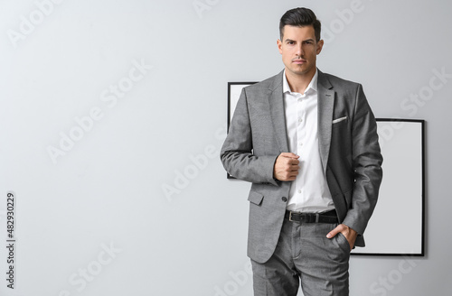 Handsome man in formal suit posing near grey wall