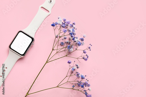 Modern smartwatch and flower on color background, closeup
