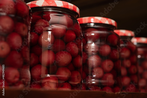 Close up of many cherry fruit compote in glass jars on a shelve. Preserved organic food, healthy homemade food concept