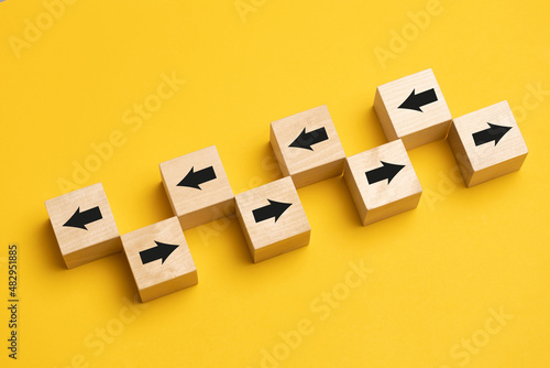 Wooden cubes with arrows moving in opposite directions. Concept of competition, diversity, confrontation or confrontation.