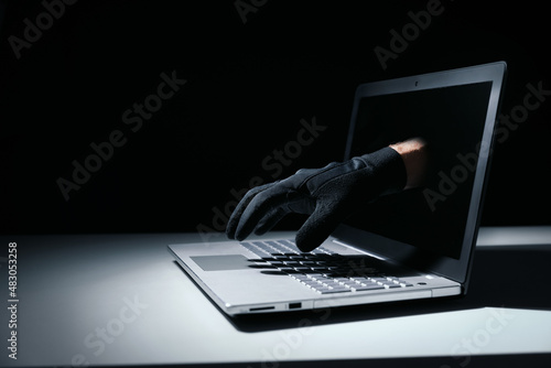 internet fraud and cyber attack concept. thief hand out of laptop screen