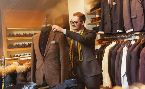 Portarit of a tailor while making a suit in clothing store. Concept: Fashion, tailoring, shop.