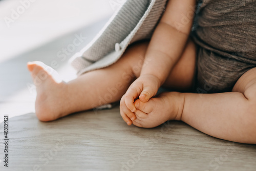 Closeup of barefoot feet of a baby sitting on a parquet floor at home.