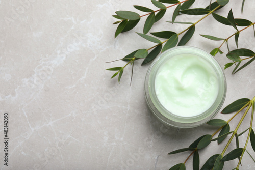 Jar of organic cream and eucalyptus on light marble table, flat lay. Space for text