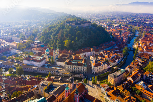 Panoramic aerial view of Ljubljana downtown with ancient castle complex on hilltop in sunny autumn morning, Slovenia