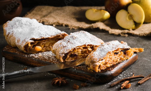 Apple pie - strudel or apfelstrudel, sliced ​​pie with apples and spices on a gray table, close-up, selective focus. Traditional pies of European cuisine