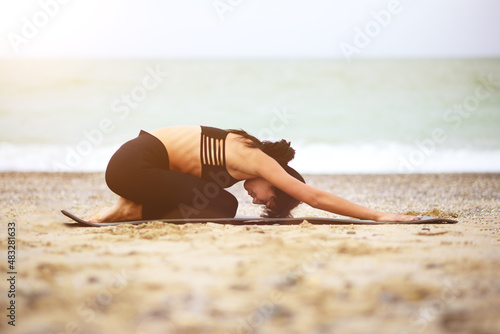Nice portrait of young beautiful darkhaired woman stretching her back on the seaside. Yoga exercising. Yoga sport. Healthy wellness lifestyle. Spiritual health. Personal fulfillment.