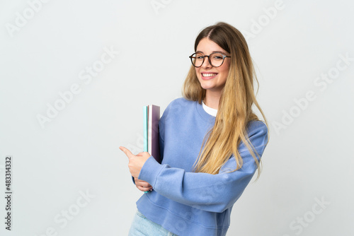 Young blonde student woman isolated on white background pointing back