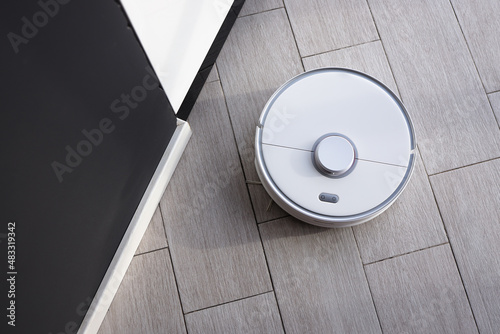 Robot vacuum cleaner removes dust in room on floor. Vacuum cleaner in ordinary apartment. modern household wireless device for cleaning house. smart home concept