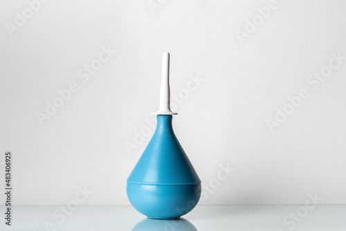 Medical rubber enema on a glass shelf on white background.