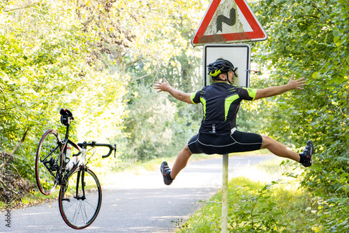 A falling cyclist bumps into a road sign warning about road with turns.